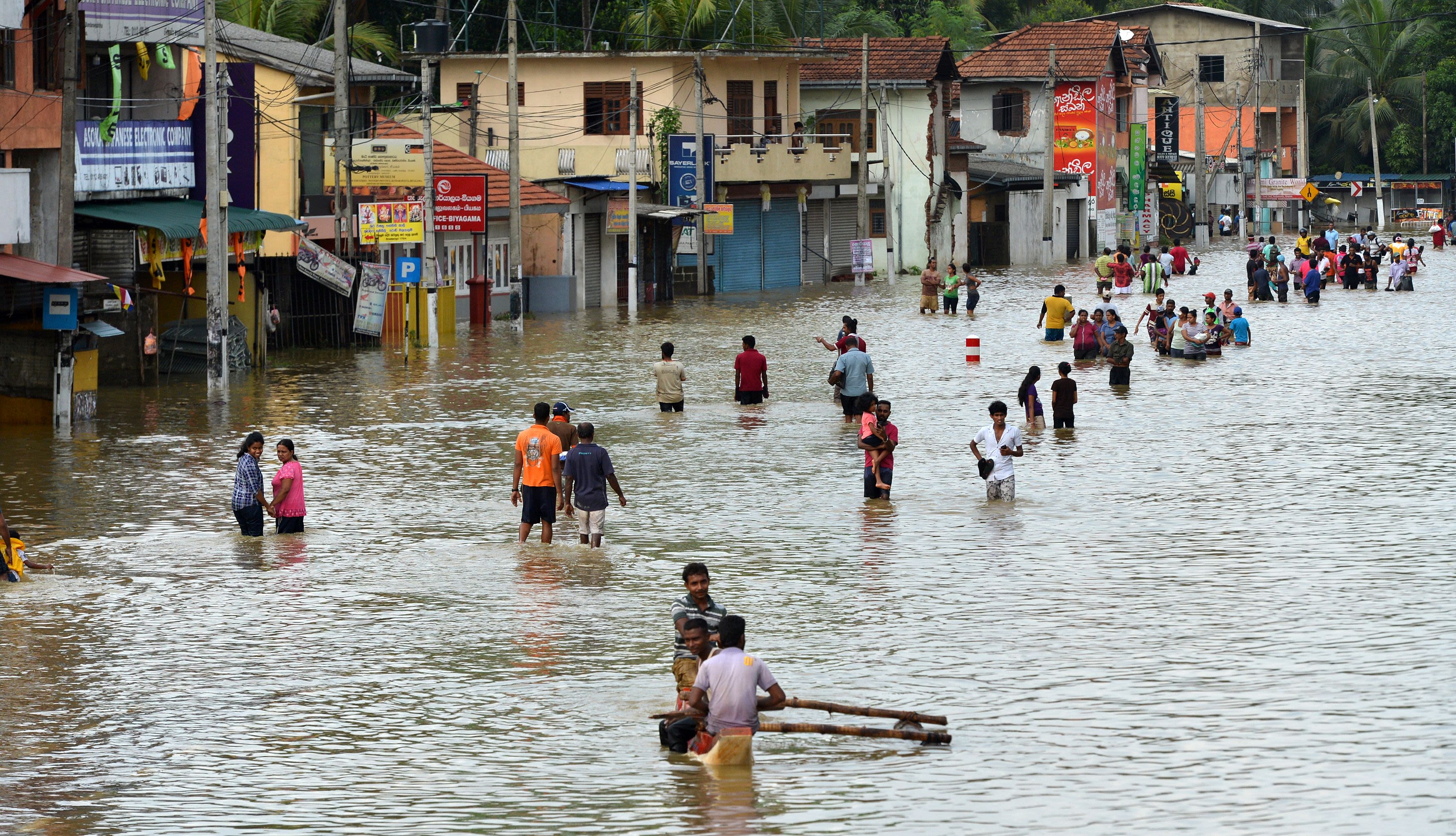 People struggling through dangerous floodwaters in Sri Lanka